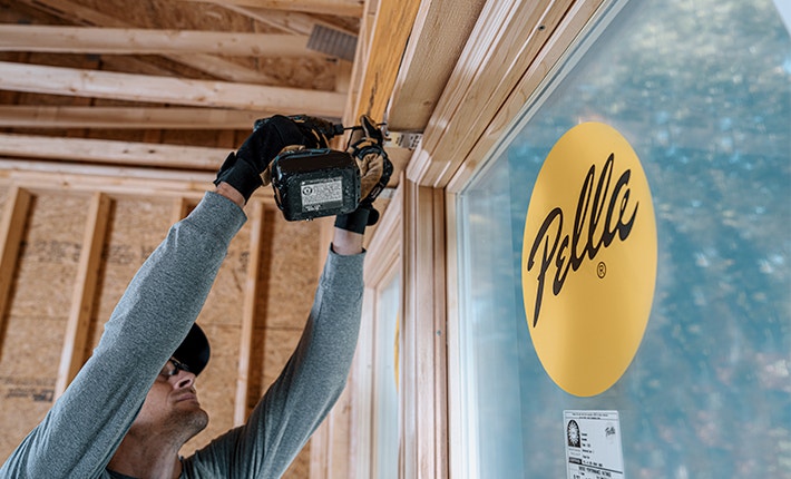 the Pella dot is labelled on a new wood window that is being installed into a home that is under construction