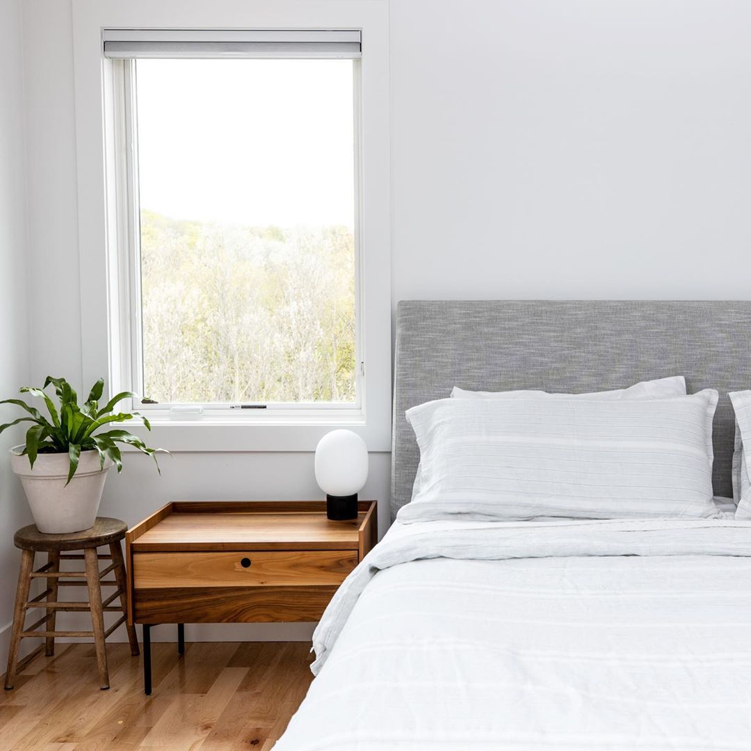 light and bright minimalist style bedroom with large casement window, nightstand, and plant