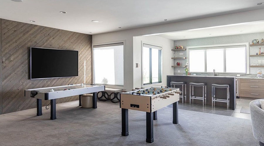 Gameroom with carpet and a small kitchenette in a home's basement.