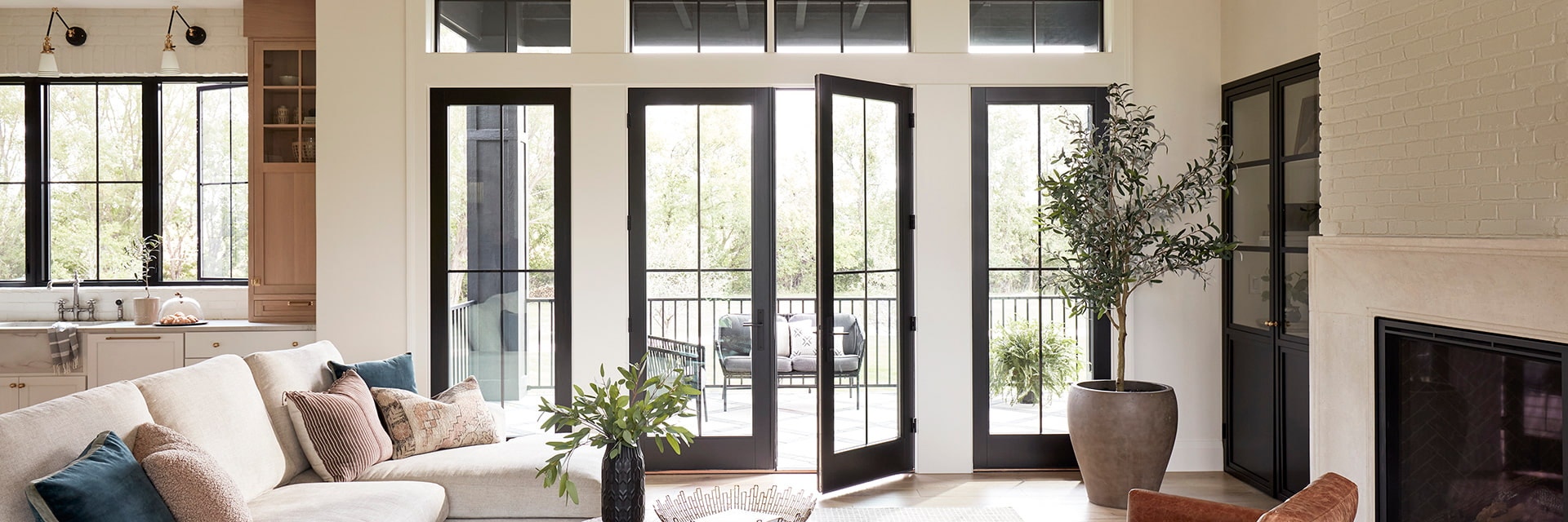 Kitchen into living room with tall black french doors open up to deck.