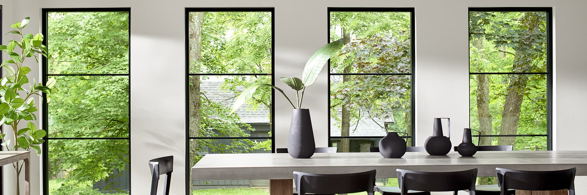 four floor-to-ceiling fixed windows behind a contemporary dining room table