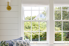 two white double-hung windows behind a blue-and-white chair