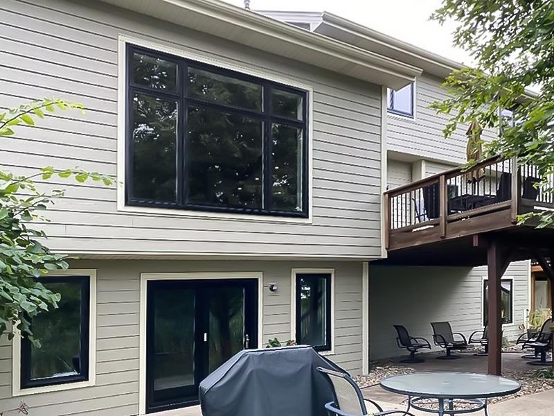 The back of a two-story home with a window unit that has black trim.
