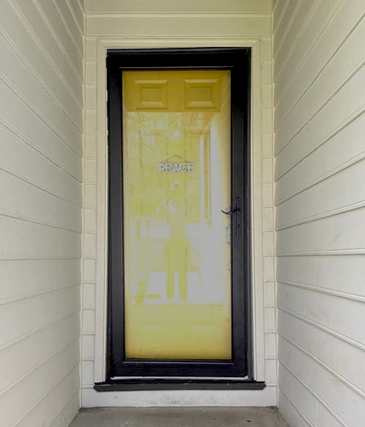 an old yellow front entry door with a black storm door on a white home