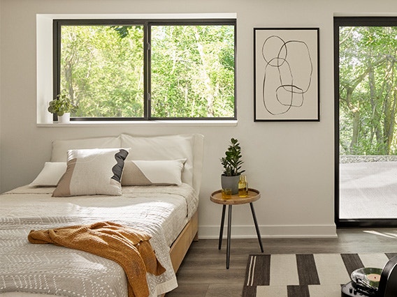 A child's bedroom with black-trimmed sliding windows and modern artwork