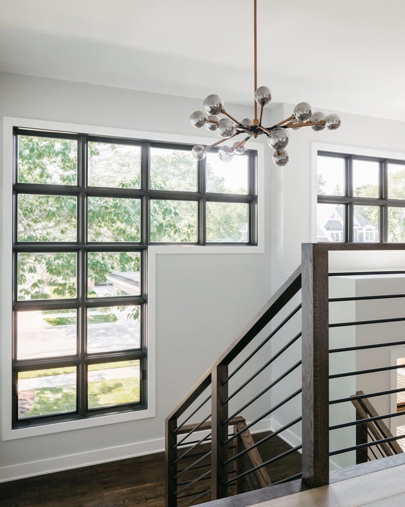 This staircase has horizontal black balusters and modern black windows.