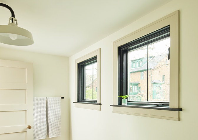 A contemporary table sits in front of three floor-to-ceiling casement windows