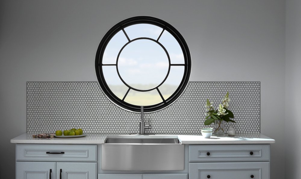 Black round window with decorative glass over farmhouse style kitchen sink