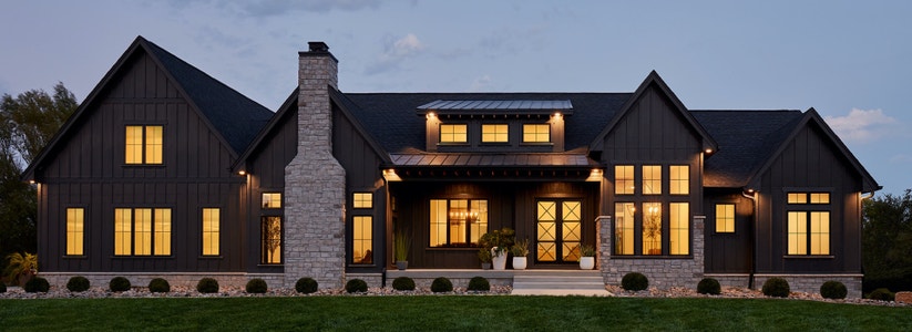 home exterior at dusk stone chimney impervia fiberglass windows