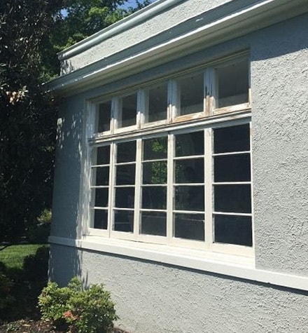an old, faded window set on a gray colonial home