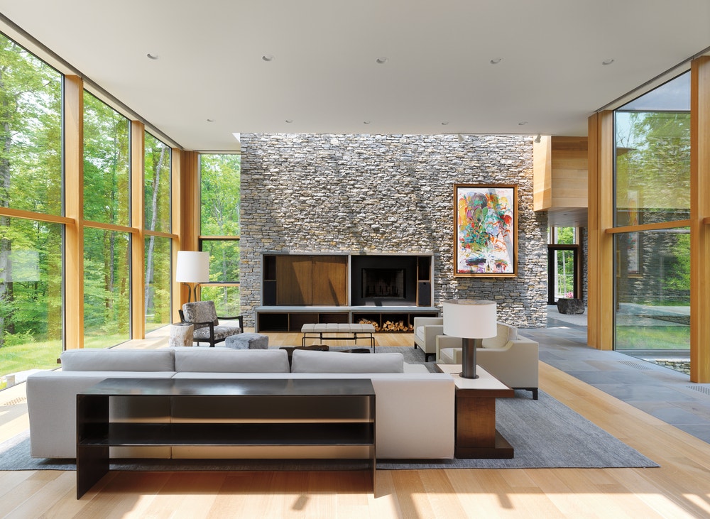Modern living room with stone wall in the front surrounded by walls fixed wood windows on either side