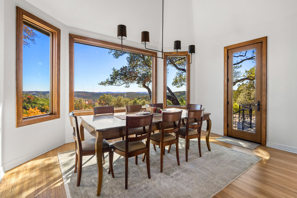 Modern dining room with large wood-trim windows and scenic outdoor view.