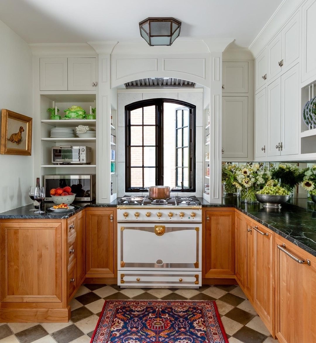 In a kitchen is a black arch window over stove.