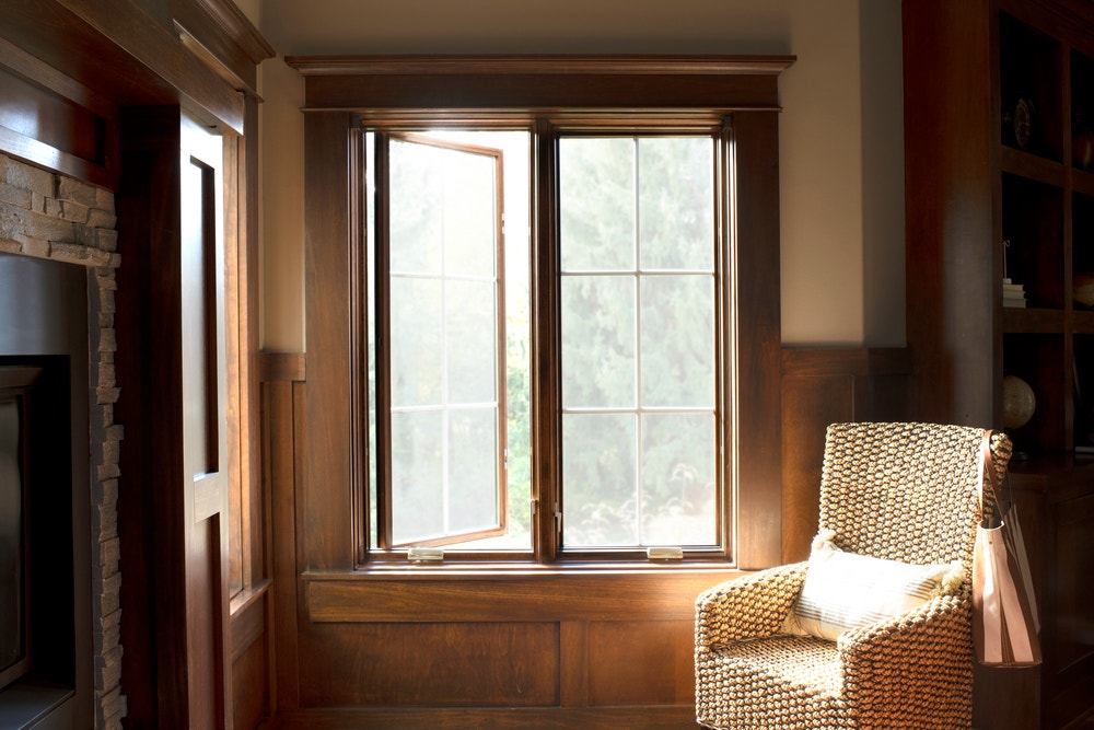 Wood paneled home office with two wide stained casement windows one opened and one closed