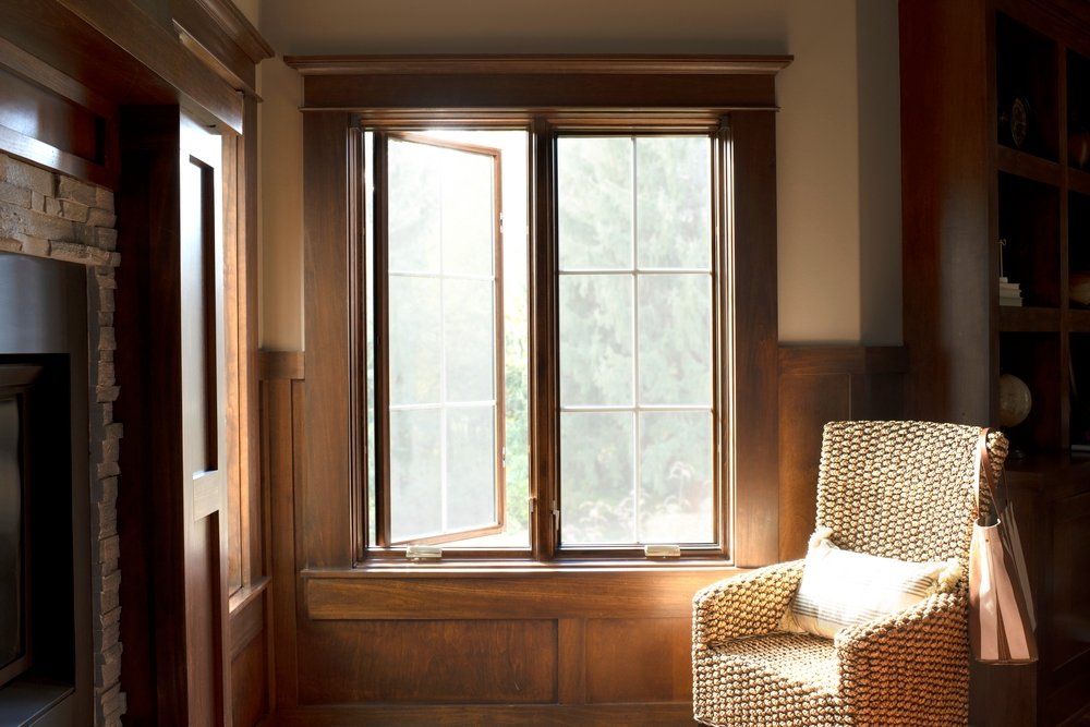 Wood paneled home office with two wide stained casement windows one opened and one closed