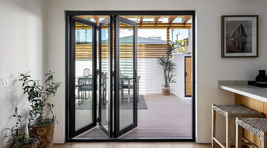Black bifold patio doors on the interior of a white-walled southwestern home.