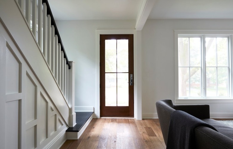 white farmhouse style entryway with stairs leading to stained wood glass front door