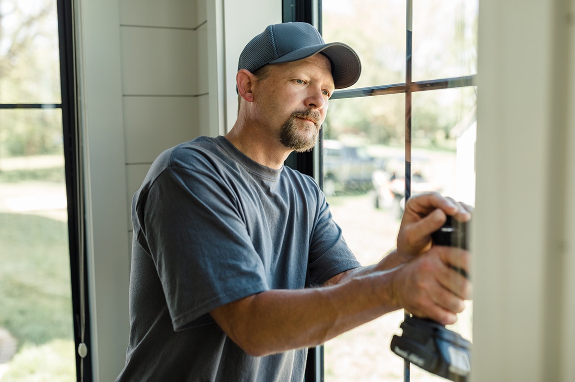 A man using tools to install a replacement window, demonstrating replacing a replacement window.