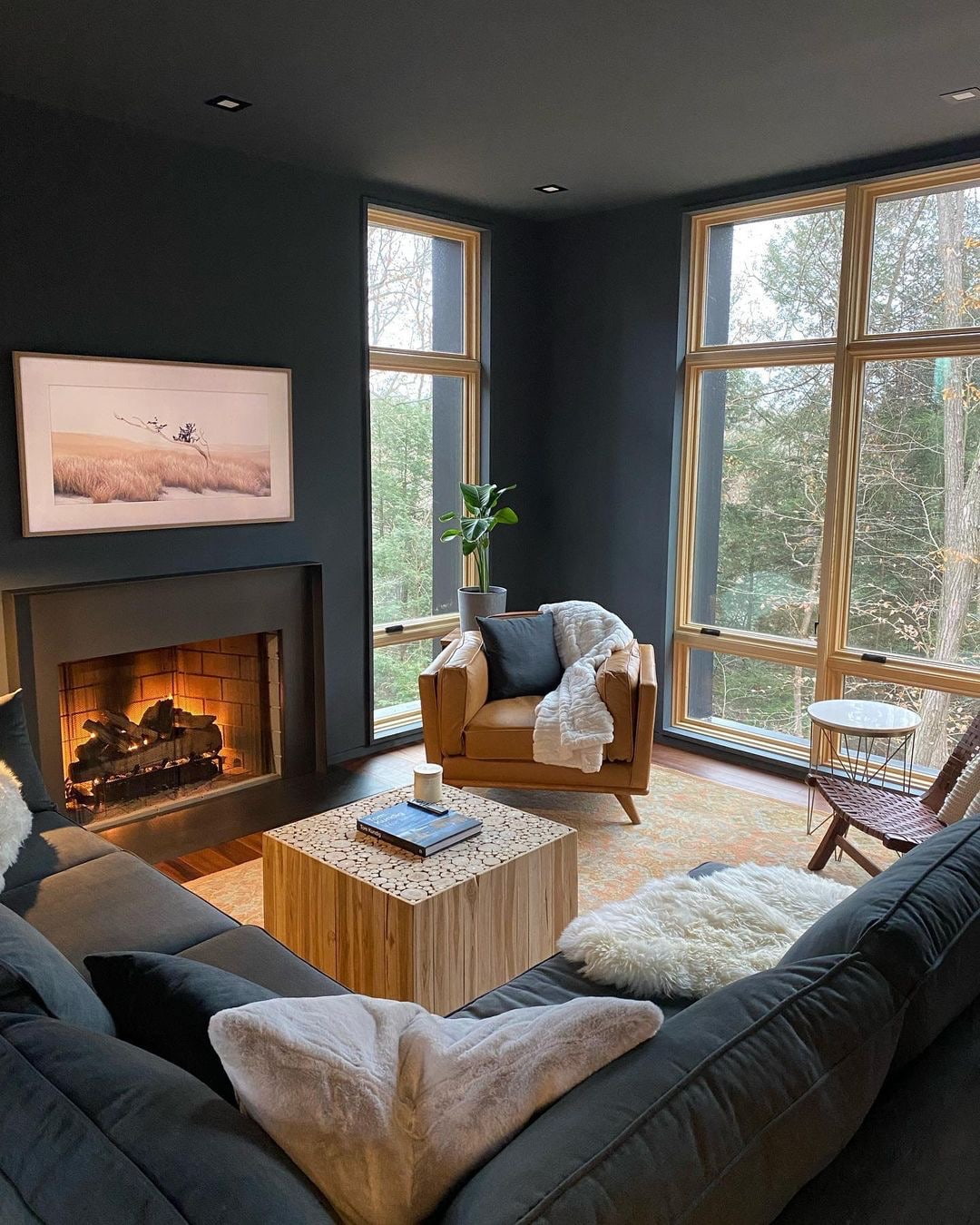 Natural pine wood windows bring light to a cozy and moody living room with a sectional and fireplace.