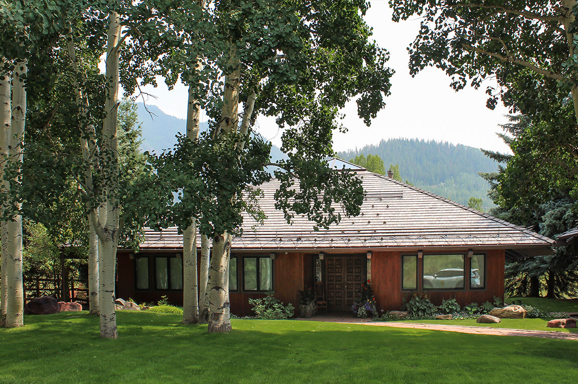 Aspen Energy Efficient home with wood siding surrounded by aspen trees and a lush green lawn.