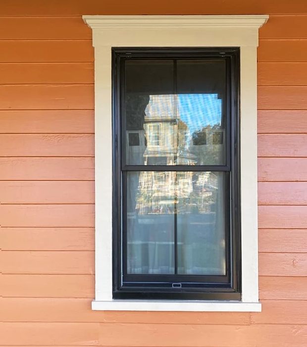 Closeup view of a newly installed black Pella double-hung window.