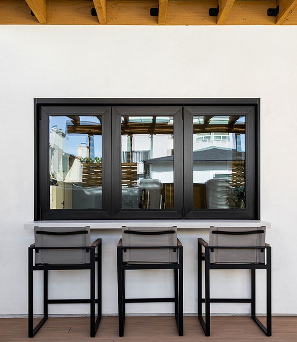 a three-panel bifold window opens from the interior kitchen to an outdoor bar