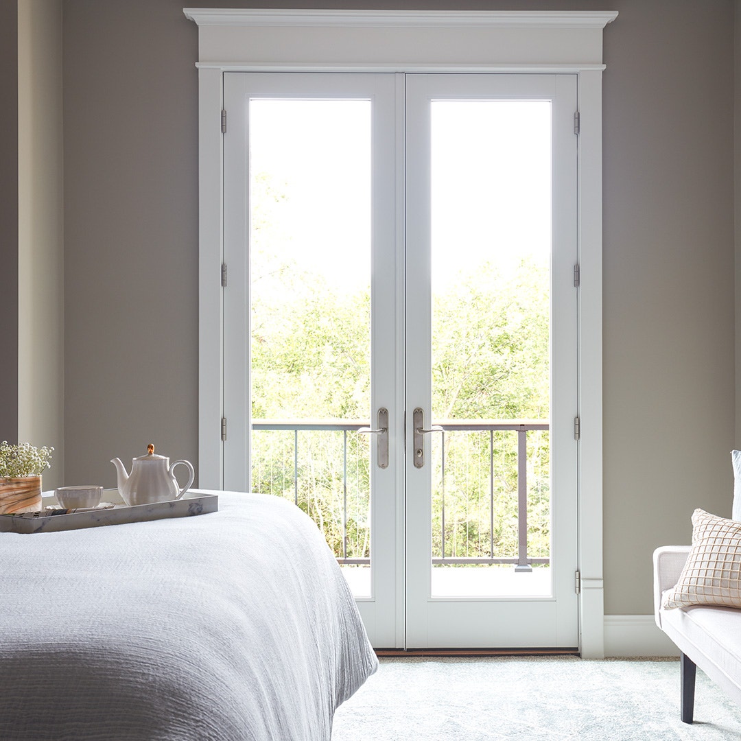 a white french door opening from a traditional bedroom to a small balcony