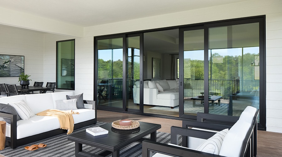 Close-up view of modern black sliding patio door hardware next to a stone accent wall.