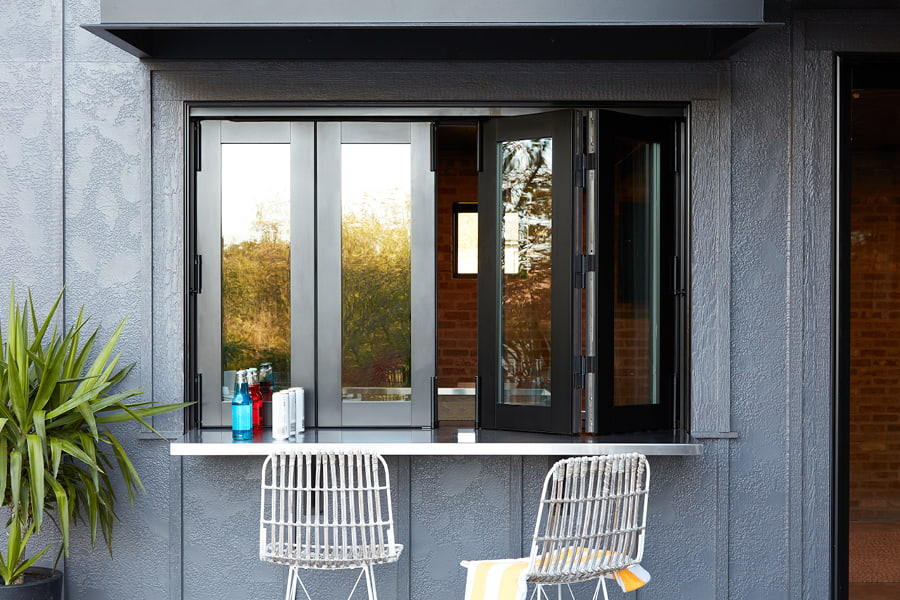 Black bifold windows with two white chairs next to counter outside