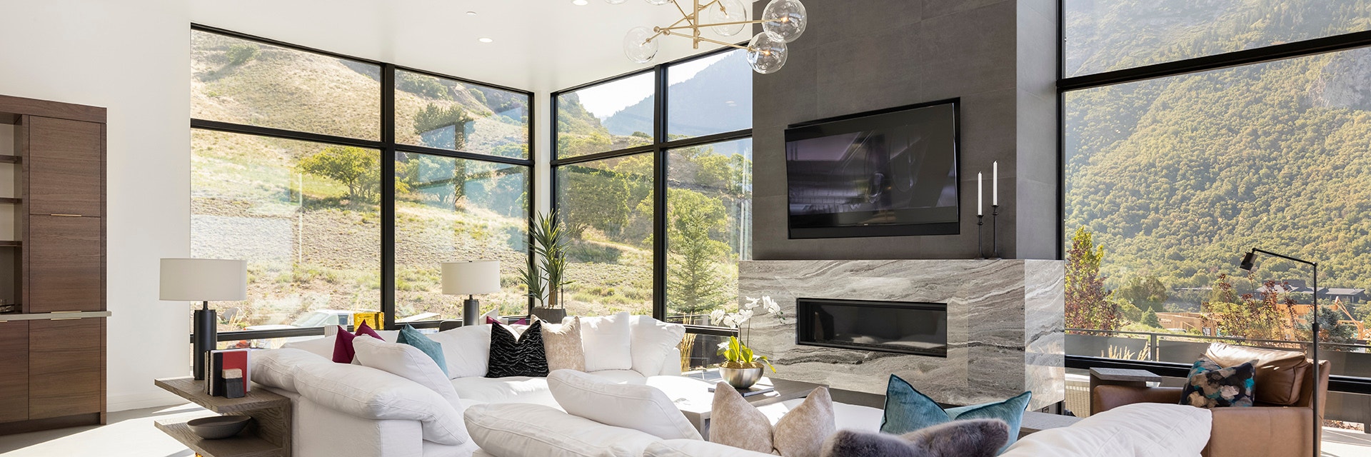 A contemporary kitchen with a large island, four barstools and a set of contemporary windows behind a china cabinet