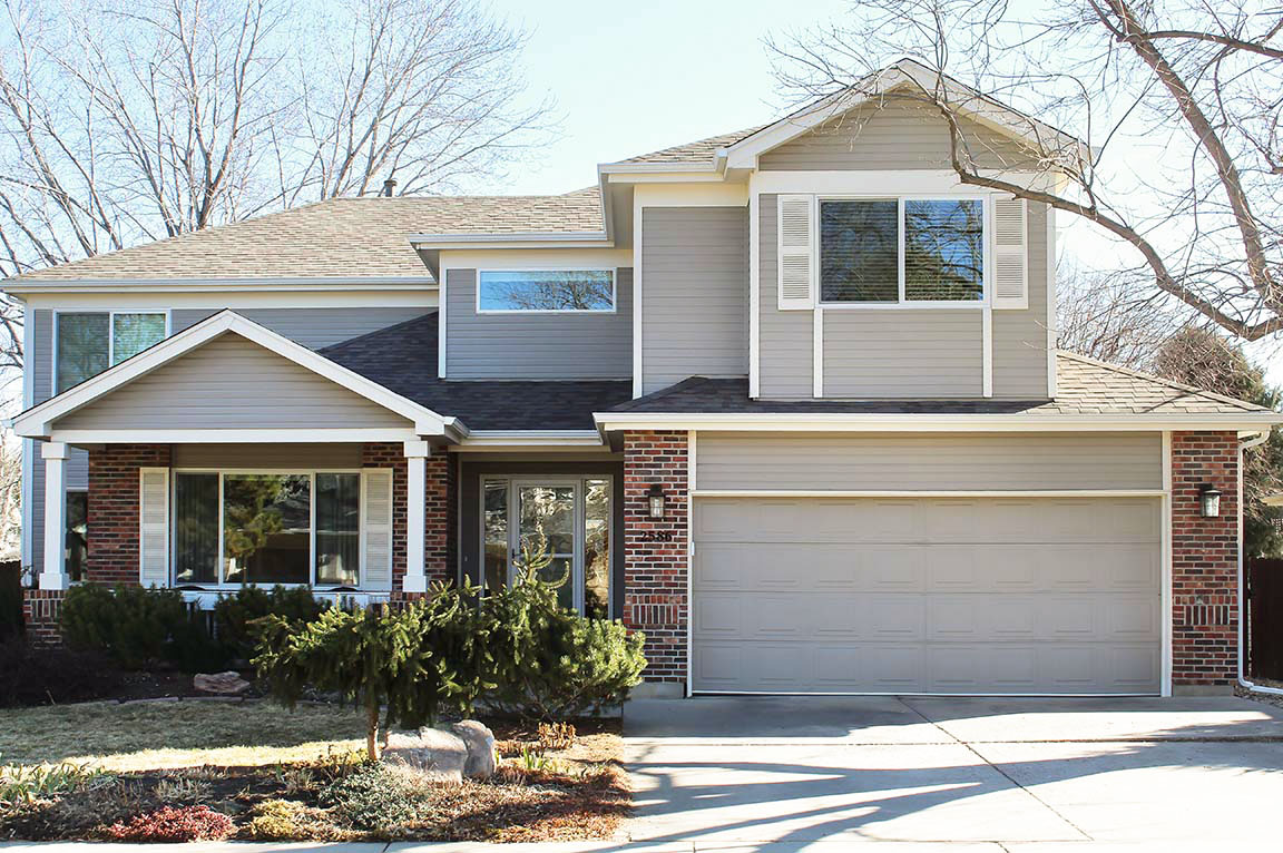Front exterior of suburban two‑story home with attached garage and landscaped yard.