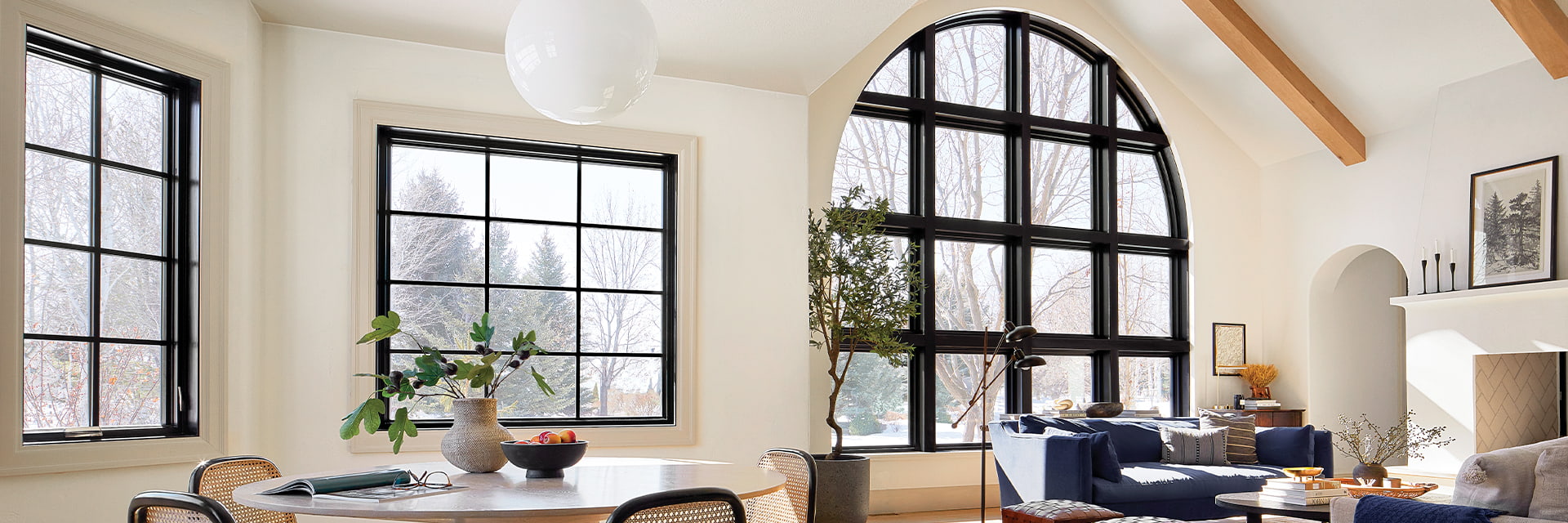 A large custom arched window unit sits to the right of a classic black-trimmed casement window
