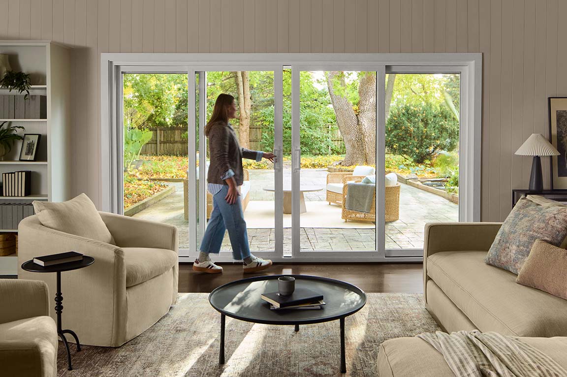 White sliding patio doors opening from a bright living room to a backyard patio.