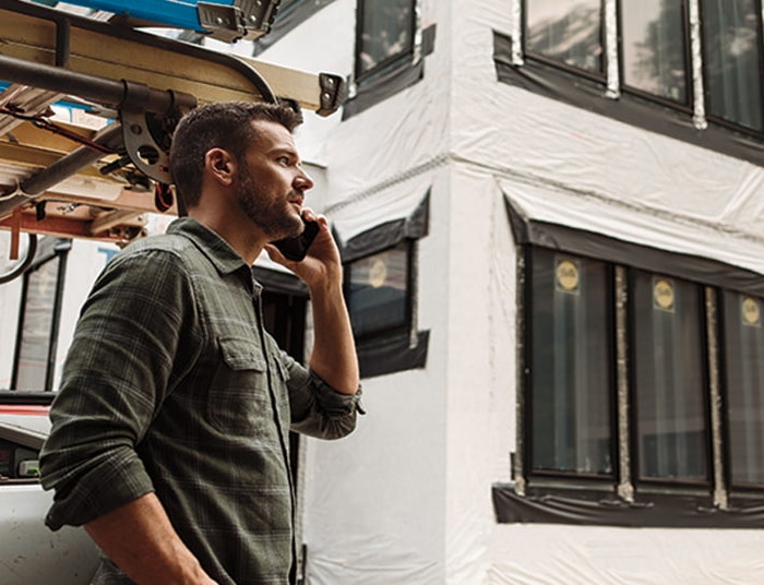 pella pro dealer talking on a phone outside a home under construction