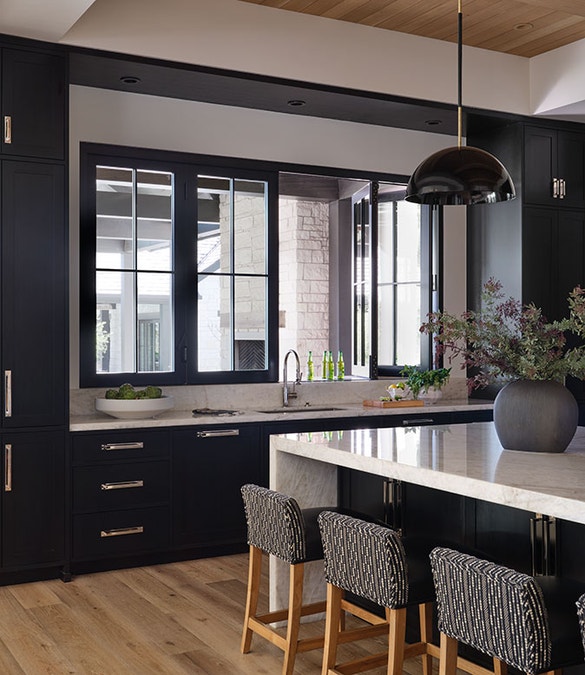 A black bifold window sits over a luxury kitchen counter.