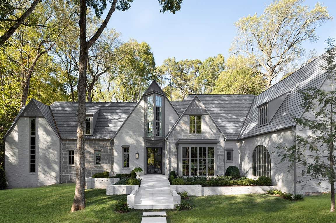 Light gray stone house featuring large front windows using a traditional grille pattern.