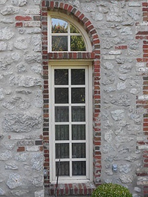 an outdated casement window with an arched transom on a Tulsa home