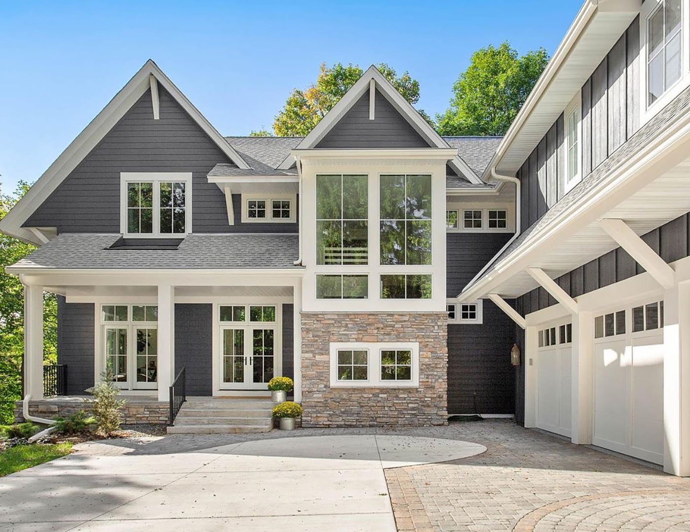 A blue home features white farmhouse windows with white trim and accents