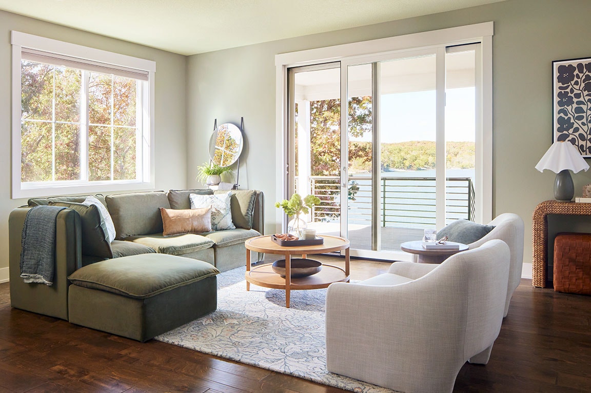 A modern living room with sliding glass doors, featuring a cozy sofa, wooden coffee table, and stylish decor, showcasing sliding door ideas.