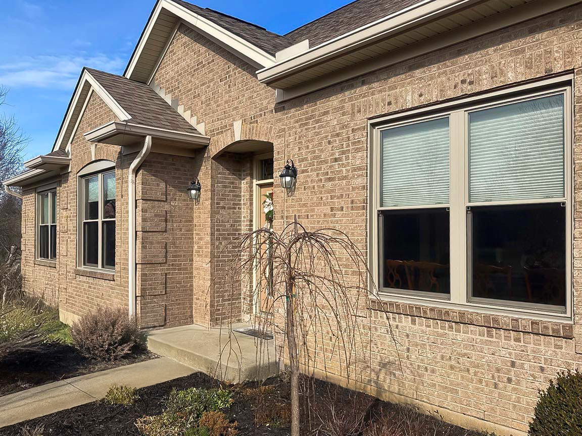 Brick home exterior featuring energy-efficient front windows and landscaped entry.