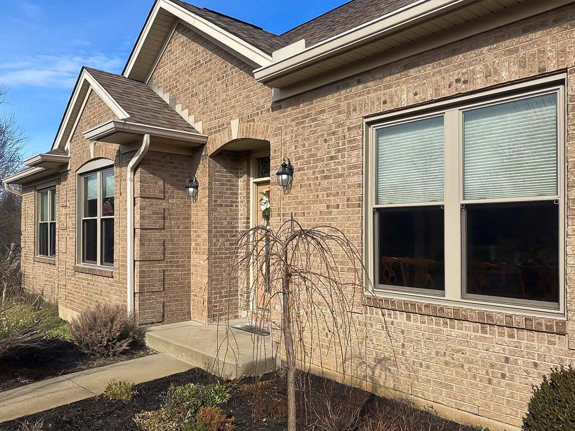 Brick home exterior featuring energy-efficient front windows and landscaped entry.