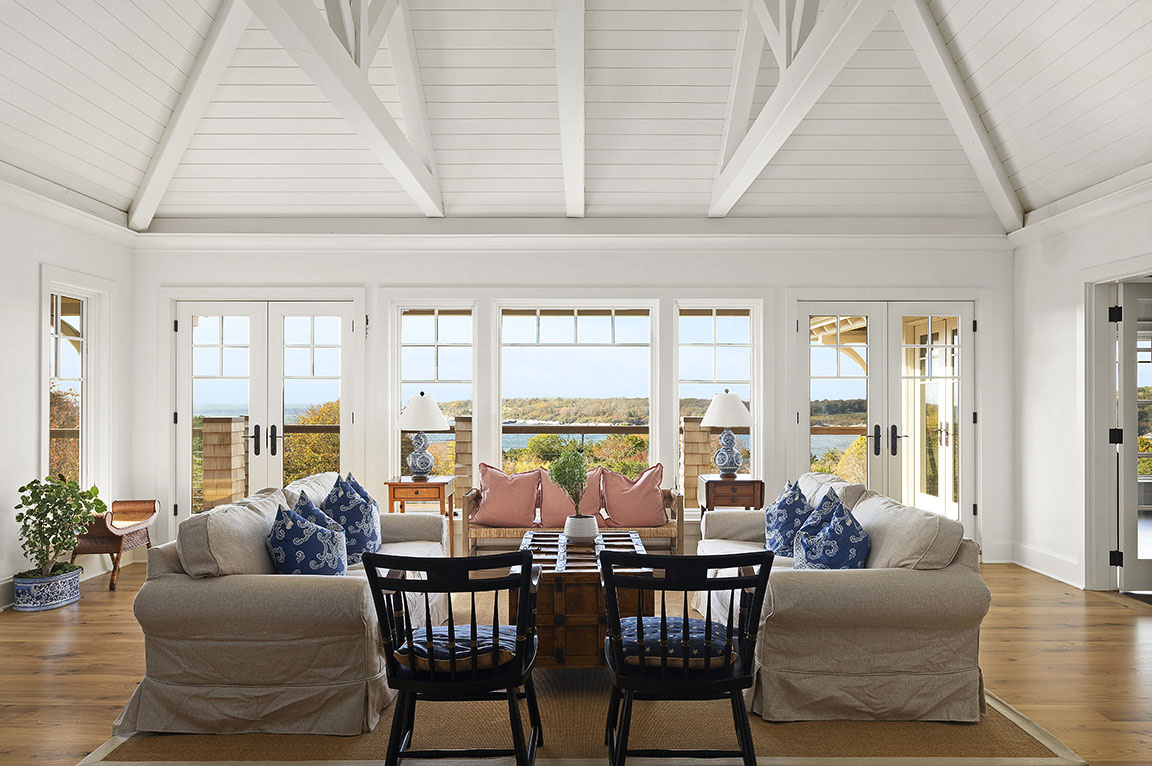 Coastal living room with large windows and vaulted ceiling.