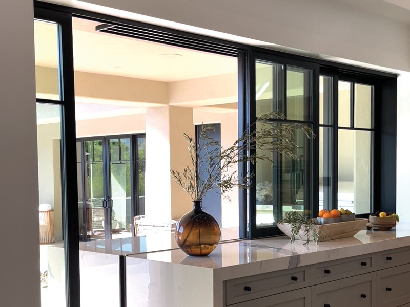 Open black sliding patio doors in the kitchen leading to outdoor entertainment space