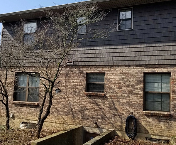 Backyard view of a traditional Okeana home with outdated windows in need of replacement.