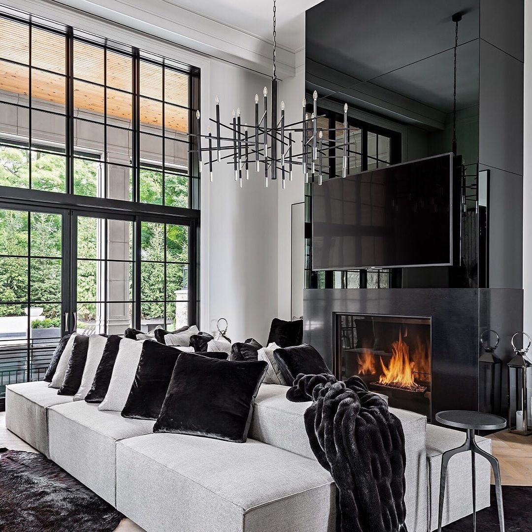 An ultra-modern black and white living room has a wall of glass with black windows and a sliding patio door.
