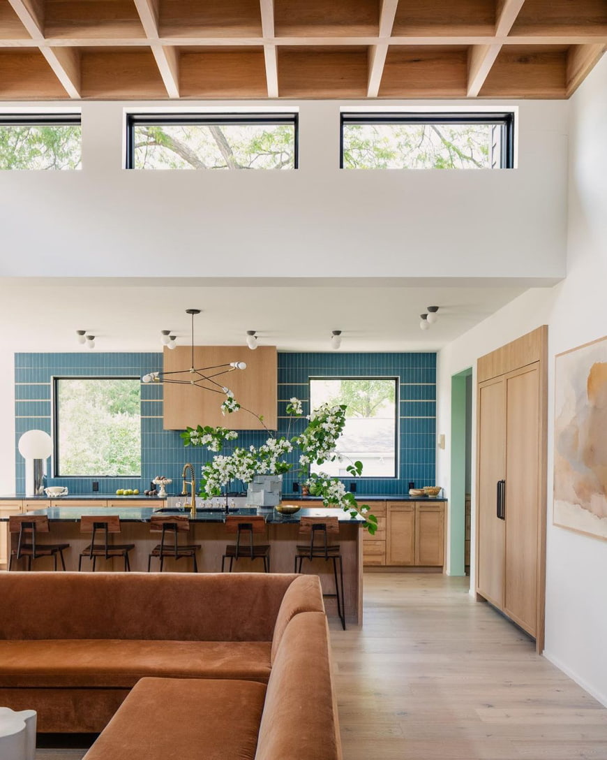 Clerestory windows above a living room allow natural light in, brightening the kitchen in the background.