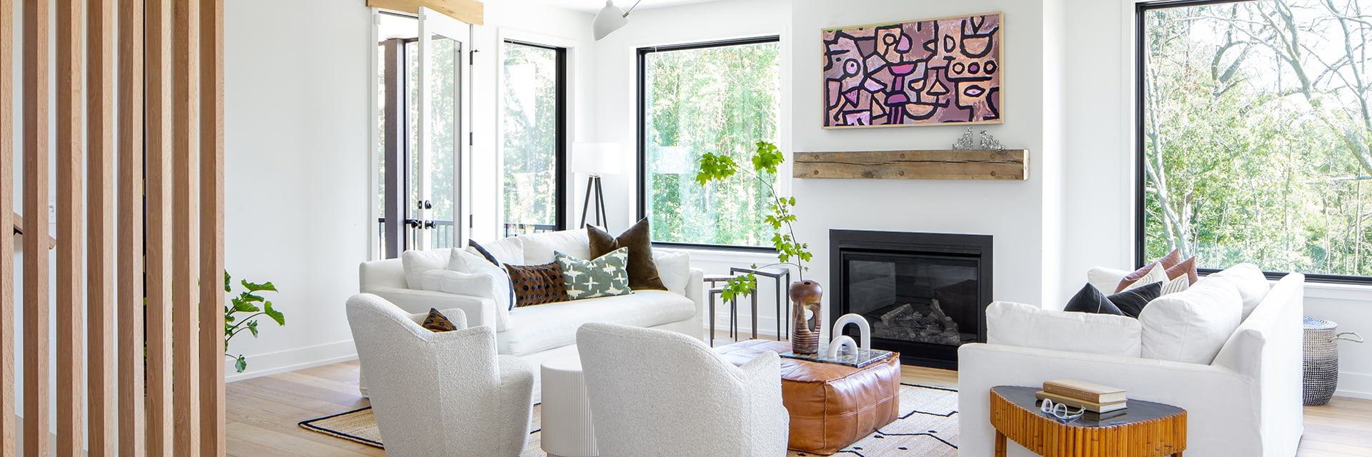 White furniture in a contemporary living room with white walls and black picture windows
