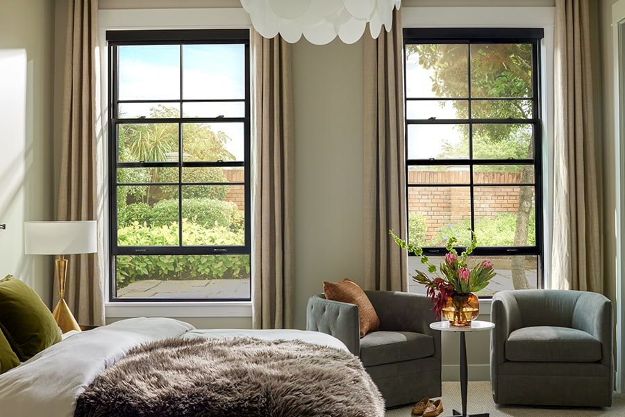 two double-hung windows behind a bed with a faux fur throw draped across the bed.