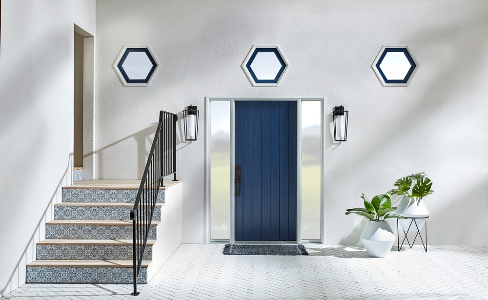 gray entryway with navy front door, mosaic tile steps, and three hexagon shape windows above the doorway