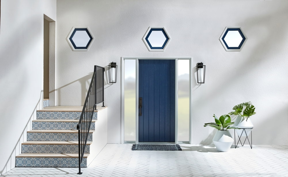Custom Hexagon Windows Featured In Unique Entryway Design gray entryway with navy front door, mosaic tile steps, and three hexagon shape windows above the doorway